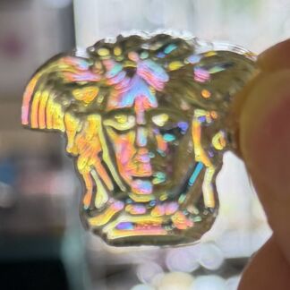 Close-up of a resin ring embedded with rainbow sprinkles, flashing pink, blue, yellow, and green colors, held near a finger.