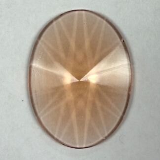 Close-up of an oval brushed-metal surface with a radial, starburst-like pattern from the center.